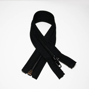 May include: A black zipper with a metal slider. The zipper is closed and folded in half.