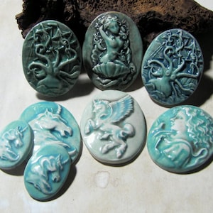 May include: A selection of ceramic cameos in teal and white. The cameos depict mythological figures such as a mermaid, a pegasus, and a unicorn. Other designs include an octopus and a ship.