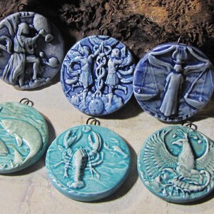 Peut inclure: Collection de six pendentifs en céramique représentant des signes du zodiaque. Les pendentifs ronds présentent des motifs en relief en bleu et turquoise. Les pendentifs sont prêts à être accrochés.