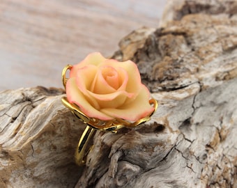 Bague en métal doré, réglable, agrémentée d'une rose,  modelée à la main en  porcelaine froide,