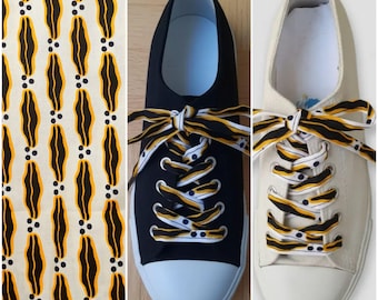 Pair of extra-long African-style shoelaces with a black, white, and yellow wax print lip or mouth design.