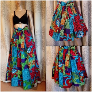 Può includere: Una gonna maxi colorata con un design a patchwork in tonalità rosso, blu, verde e arancio. La gonna ha un'alta vita e un nodo sul davanti.