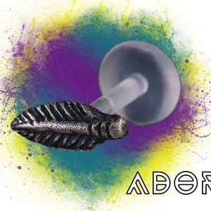 May include: Silver feather shaped body jewelry with a clear plastic post and backing. The jewelry is set against a colorful background with the word "ADORE" in black text.
