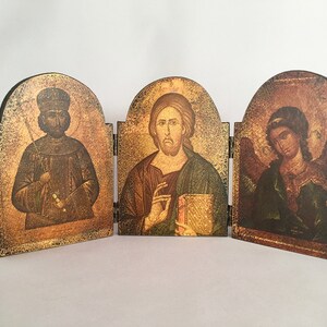 May include: A wooden triptych with three panels, each featuring a religious icon. The left panel depicts a man with a crown and a staff, the middle panel shows a man with a book, and the right panel shows a person with wings.