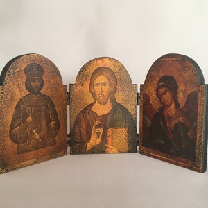 May include: A wooden triptych with three panels, each featuring a religious icon. The left panel depicts a man in a crown and robe, the center panel shows a man with a beard and a book, and the right panel shows a person with wings and a halo.