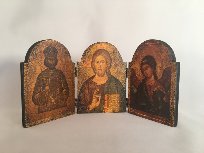 May include: A wooden triptych with three panels, each featuring a religious icon. The left panel depicts a man in a crown and robe, the center panel shows a man with a beard and a book, and the right panel shows a person with wings and a halo.