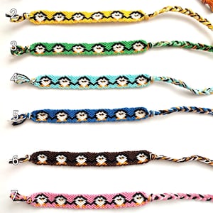 May include: Seven colorful friendship bracelets with a penguin pattern. The bracelets are made with different colored threads and have a white background with black outlines. The bracelets are numbered 1 through 7.