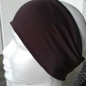 May include: A black headband made of soft fabric. The headband is wide and has a simple design.
