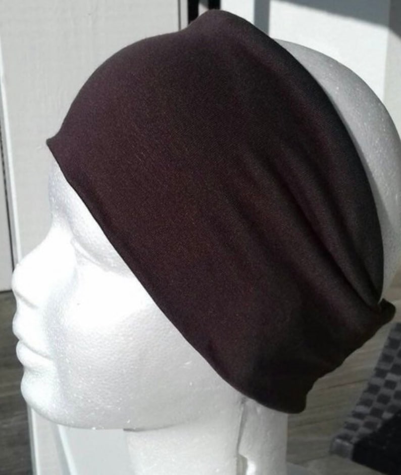 May include: A black headband made of soft fabric. The headband is wide and has a simple design.