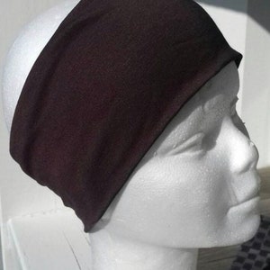 May include: A black headband made of soft fabric. The headband is worn on a white mannequin head.