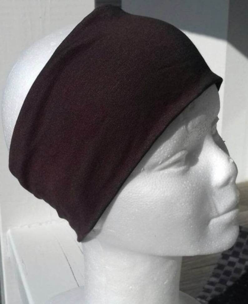 May include: A black headband made of soft fabric. The headband is worn on a white mannequin head.