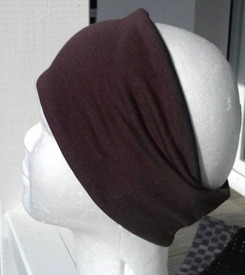 May include: A brown headband made of soft fabric. The headband is wide and has a simple design.