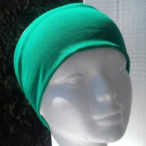 May include: A bright green headband made of soft fabric. The headband is worn on a white mannequin head.