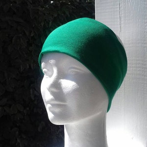 May include: A bright green headband made of soft fabric. The headband is worn on a white mannequin head.
