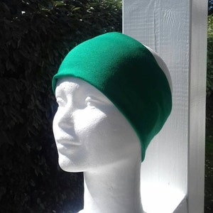 May include: A bright green headband made of soft fabric. The headband is worn on a white mannequin head.