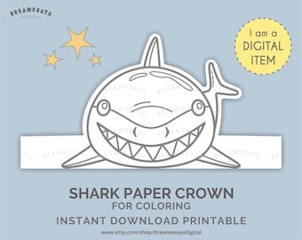 May include: A printable shark paper crown for coloring, featuring a smiling shark with sharp teeth. The design includes three yellow stars and the text "I am a DIGITAL ITEM". The Etsy shop name is also visible.