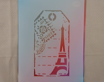 May include: A white plastic stencil with a vintage Parisian theme. The stencil features a tag with a rose, the words "Paris" and "Post", and an outline of the Eiffel Tower.
