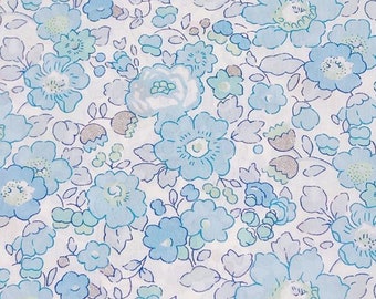 Puede incluir: Una tela blanca con un patrón floral azul. Las flores son pequeñas y delicadas, de color azul claro. La tela tiene un brillo sutil.