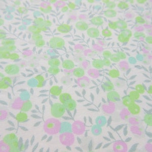 May include: White fabric with a repeating pattern of small green and pink flowers and leaves.