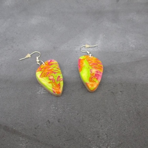 以下が含まれることがあります： 緑、ピンク、オレンジの抽象的な模様が施された、涙滴型のデザインのドロップイヤリングのペア。ポリマークレイで作られています。