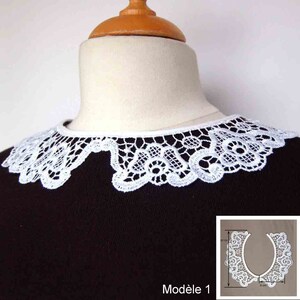 Pode incluir: Gola de renda branca, Modelo 1, exibida em um manequim. A gola tem aproximadamente 20 cm de largura e 8 cm de altura. O intrincado design de renda é visível contra um fundo escuro. Um acessório de inspiração vintage.