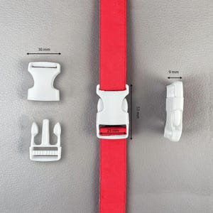 Puede incluir: Hebillas de liberación lateral de plástico blanco y una correa roja. La hebilla mide 5,3 cm de largo y 2,5 cm de ancho. La otra hebilla mide 3 cm de ancho. La tercera hebilla mide 0,9 cm de ancho. La correa es roja.