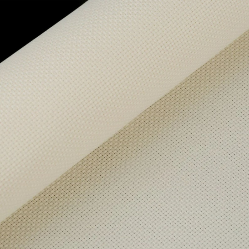 May include: Close-up of a rolled-up, off-white cross-stitch fabric. The fabric has a grid-like pattern of small holes, ideal for needlework projects. The texture is visible, with a slight sheen. The background is black.