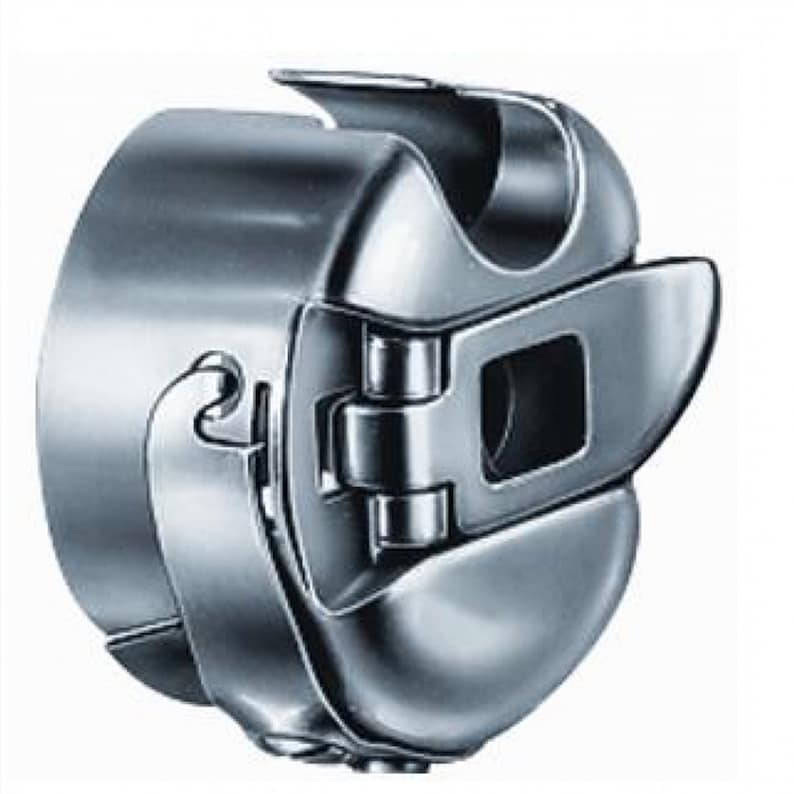 May include: A close-up of a shiny, silver-colored sewing machine bobbin case. The case has a curved design with a hinged door and a latch. The metal has a reflective surface, and the overall shape is rounded.