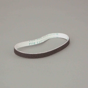 Puede incluir: Una banda de lijado marrón con texto blanco "FOR EAST MAN MEDIUM". La banda tiene forma de bucle y está diseñada para herramientas eléctricas. El fondo es de color gris liso.