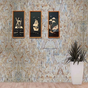 Pode incluir: Três obras de arte emolduradas com molduras de madeira e fundos pretos. As obras retratam um moinho de vento, um veleiro e uma paisagem com árvores e uma casa. O fundo é uma parede com um design de lascas de madeira, e há um vaso branco com uma planta.