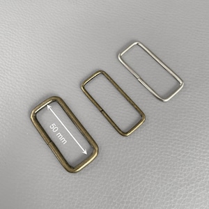 Peut inclure: Trois anneaux rectangulaires en métal de tons laiton antique, argent et bronze. L'anneau en laiton antique mesure 5 cm de long. Ces anneaux sont probablement utilisés pour la fabrication de sacs ou d'autres projets d'artisanat.