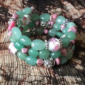 Op de afbeelding: Een meerstrengige armband met groene jade, roze en witte bloemen kralen en zilveren accenten.