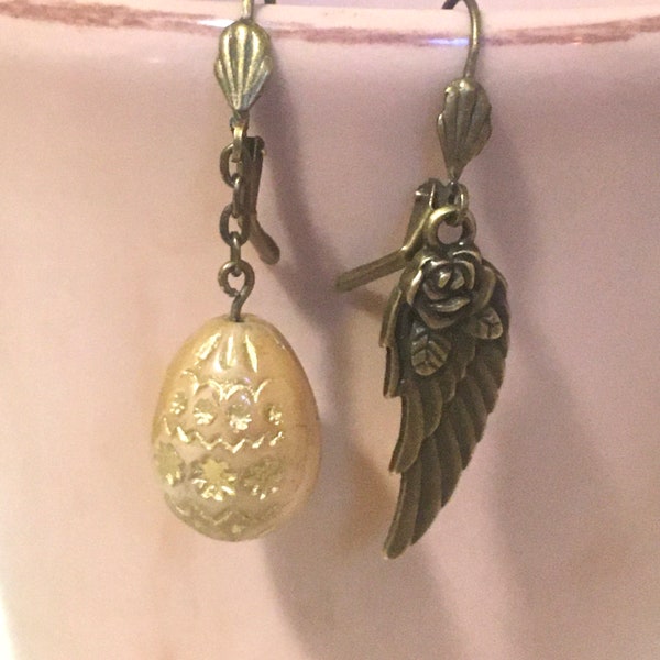 Asymmetrical sleeper earrings with creamy beige egg and 3D gold in Bohemian glass and two-sided bronze angel wing decorated with a rose