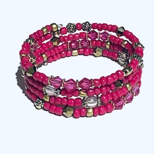 Puede incluir: Una pulsera envolvente de múltiples hilos con cuentas rosas vibrantes, acentos dorados y plateados. La pulsera incluye cuentas de cristal rosa y transparente facetadas y dijes decorativos de flores metálicas.