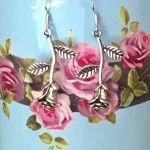 Antiqued silver rose charm earrings on dangling stems/branches. Romantic, bucolic, vintage.