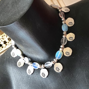 Blue, silver, transparent choker necklace in flat oval opal beads, faceted rock crystal, openwork leaf sequins