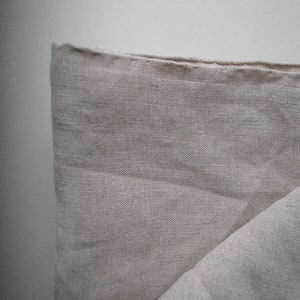 Może przedstawiać: Zbliżenie na złożony kawałek beżowego materiału lnianego. Materiał ma naturalny, fakturowany wygląd i fakturę.