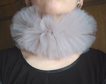 May include: A large, fluffy, white tulle collar. The collar is worn around the neck and is made of many layers of tulle.