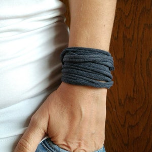 Könnte beinhalten: Ein dunkelgraues Stoffarmband, das um das Handgelenk einer Person gewickelt ist.