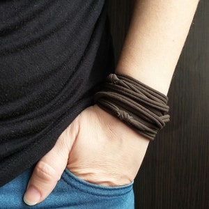 Könnte beinhalten: Ein braunes Stoffarmband mit mehreren Schichten, das an einem Handgelenk getragen wird.