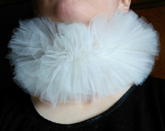 May include: A white tulle collar with a ruffled design. The collar is worn around the neck and is a fashion accessory.