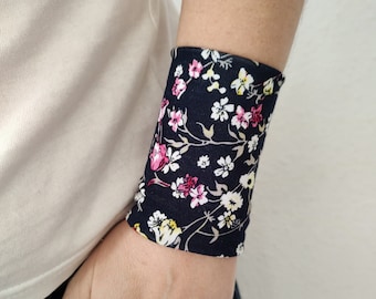 Può includere: Un braccialetto nero con un motivo floreale rosa, bianco e giallo. Il braccialetto è realizzato in tessuto e ha una sensazione morbida e confortevole.  Organic Floral.