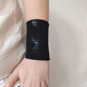 Pu&ograve; includere: Bracciale nero per polso con un design a farfalla bianca.
