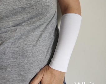Puede incluir: Se muestra una manga de brazo blanca en un brazo. La manga está hecha de una tela lisa y opaca. La palabra "White" está escrita en la esquina inferior derecha de la imagen. La persona lleva una camiseta gris y vaqueros azules.