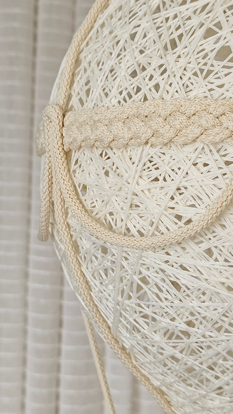 May include: A white string light with a braided rope detail. The light is made of a delicate, woven material and has a natural, rustic look.
