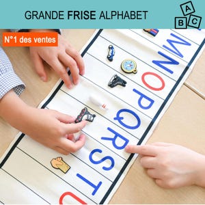 May include: A white fabric alphabet strip featuring large blue and red printed letters from M to U. The strip includes small, colourful, three-dimensional decorative icons placed within the letter sections, such as a car, compass, skate, and bowling pin.