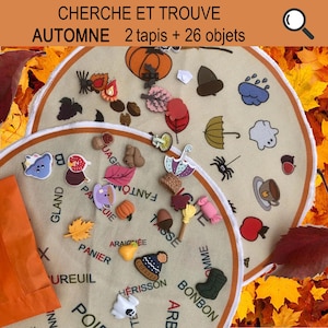 Peut inclure: Deux tapis en feutre beige avec une bordure orange, chacun présentant une variété d'images et de mots sur le thème de l'automne en français. Les tapis sont entourés de feuilles d'automne colorées. Le texte sur les tapis est "CHERCHE ET TROUVE AUTOMNE 2 tapis + 26 objets".