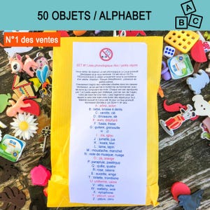 Peut inclure: Une enveloppe jaune contenant une liste de 50 objets pour l'apprentissage de l'alphabet, entourée de diverses petites figurines en plastique dont une marguerite, une clé, un dé et des formes d'animaux. Le texte liste des mots de A à Z.