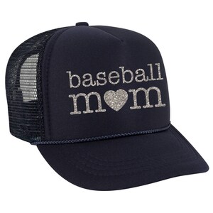 May include: A navy blue trucker hat with a black mesh back. The hat has a silver glitter design that says "baseball mom" with a heart in the middle.