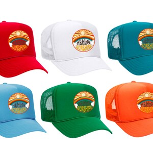 Peut inclure: Six casquettes de camionneur avec un dos en maille de différentes couleurs. Les casquettes présentent un motif soleil et nuages de style rétro avec le texte "Hello Sunshine".